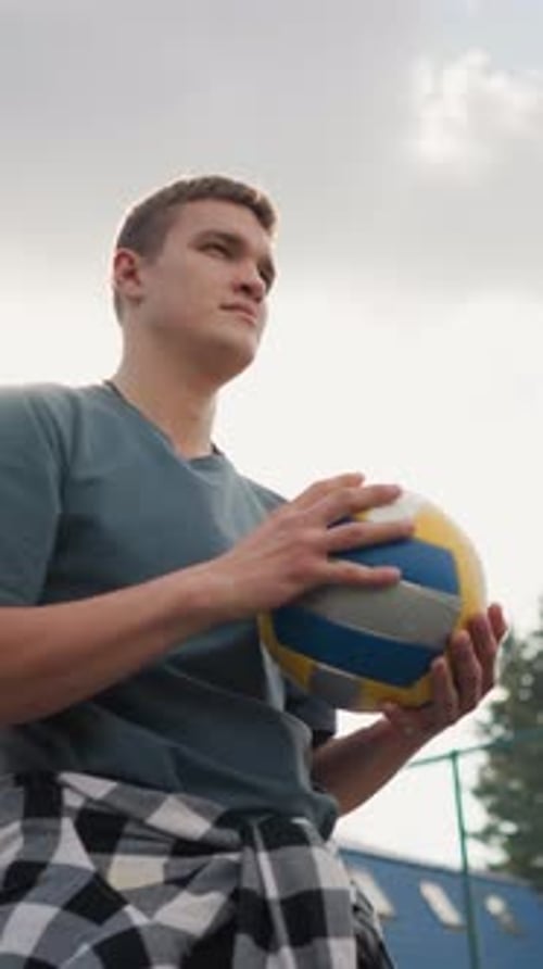 Young Man Holding Volleyball Outdoors on Bright Day