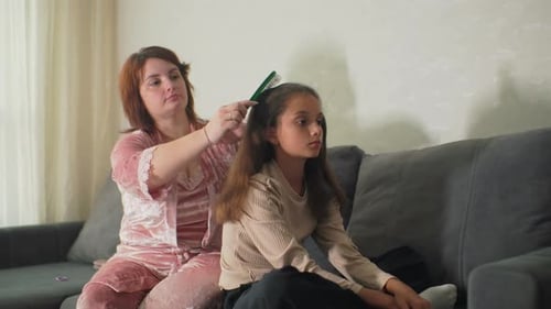 Mother Gently Combs Daughter's Hair at Home