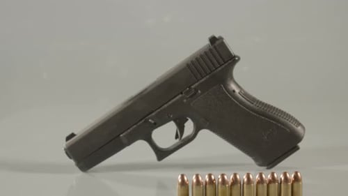 Dolly in to 9mm handgun standing beging ammunition against a white background
