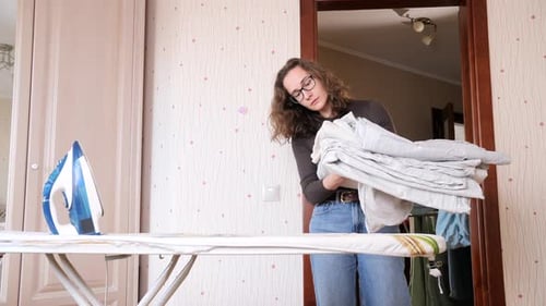 Woman Holding Stack of Ironed Linens at Home