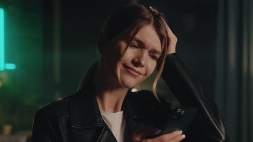 Woman Looks at Phone in Dark Urban Setting