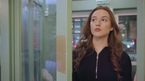Woman Enters Building Through Glass Doors at Night
