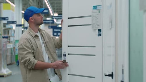 A Young Man Chooses Interroom Door in the Hardware Store