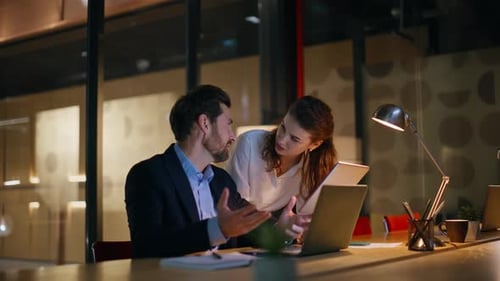 Überstundenmanager diskutieren Strategie auf einem Tablet-Laptop am Abend im Workspace Looking