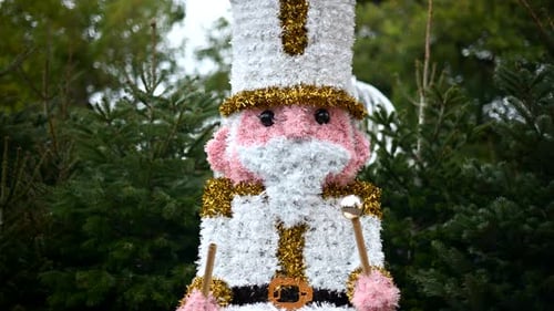 Decorative Christmas nutcracker soldier figure displayed outdoors with trees in the background