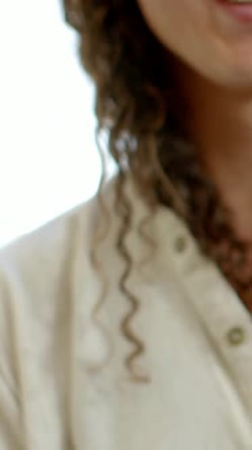 Vidéo verticale : caméra changeante révélant un adulte non binaire souriant en studio, montrant une boucle d'oreille en forme de cerceau