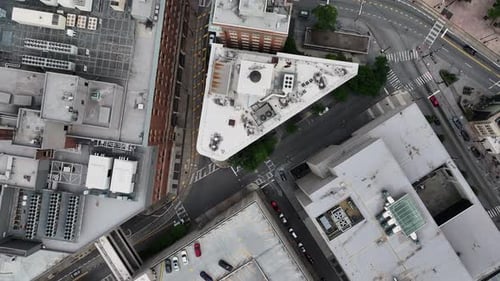 Top down panning footage of buildings and streets in urban neighborhood. Cars passing road intersect