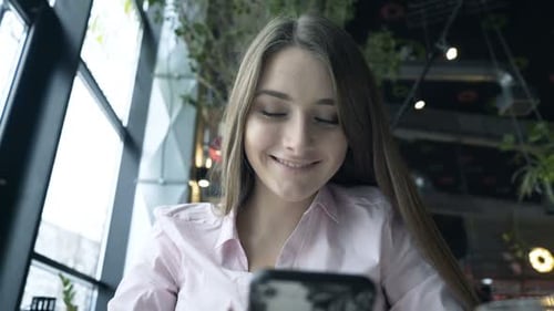 Young, Pretty Woman Using Smartphone Sitting in Cafe 20s