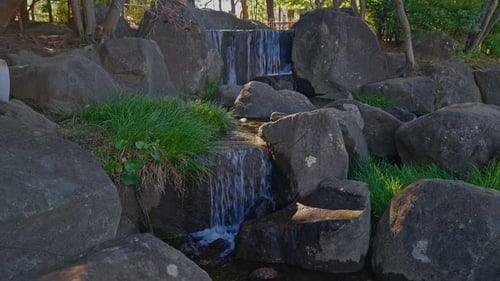 Stufenförmiger Wasserfall, der durch Felsen in einem japanischen Garten kaskadiert