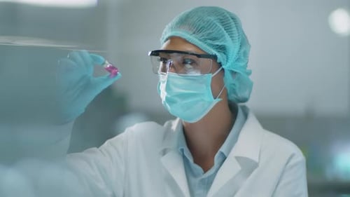 Female Scientist Examining Pink Liquid in Vial