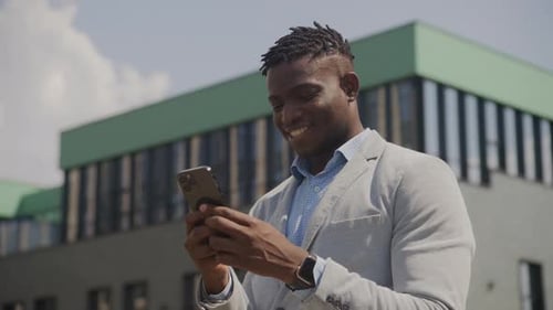 Smiling Man Using Smartphone Outside Office Building
