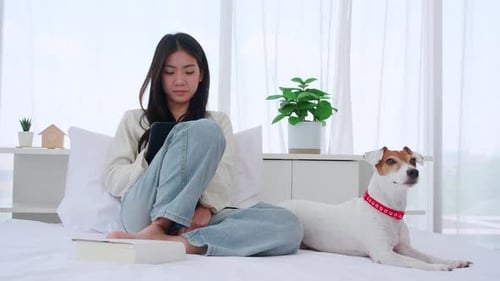 Woman Relaxing on Bed Using Tablet with Dog