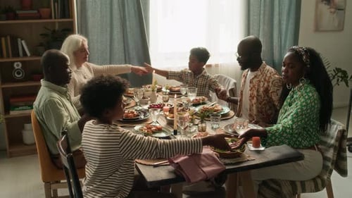 Family Holding Hands at Dinner Table