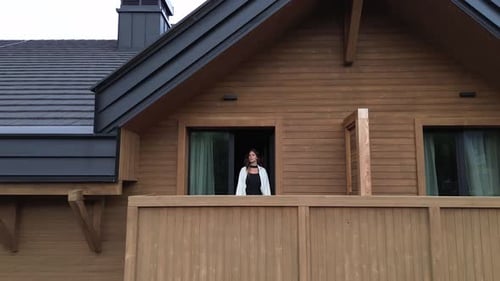 Woman On Balcony At Wooden Hotel Aerial Shot