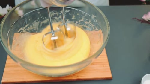 Mixing Yellow Liquid with Electric Mixer in Glass Bowl