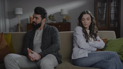 Upset Couple Sitting on Couch in Living Room