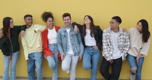 Laughing Young Adults Against Yellow Urban Wall