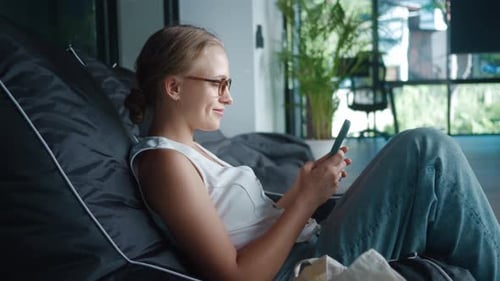 Woman Relaxing with Mobile Phone in Beanbag Chair