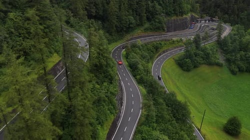 Red Car Driving on Winding Mountain Road After Rain
