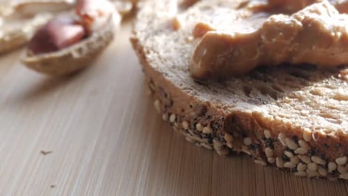 Slice of multigrain bread with creamy peanut butter on a wooden surface, close-up