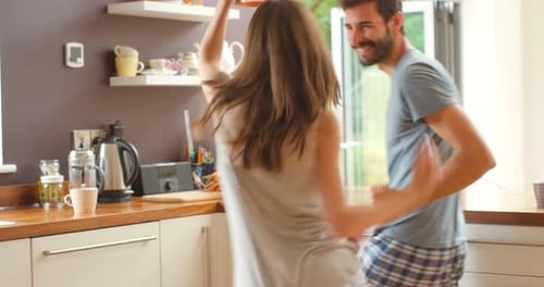 A happy young couple dancing together in their kitchen