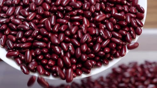 Eine weiße Schale mit Granatapfelkernen und ein Haufen roter Bohnen in Nahaufnahme