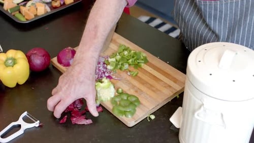Midsection of senior caucasian couple cleaning vegetable peels in kitchen at home, slow motion