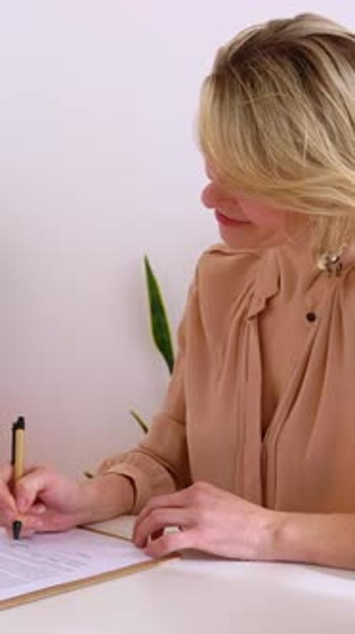 Happy Mid Adult Woman Signing Contract Agreement in the Office