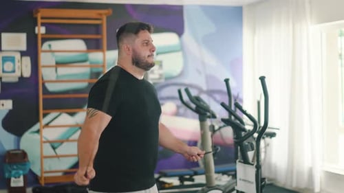 Strong young man using a jumping rope to improve muscle strength and cardio routine in the gym