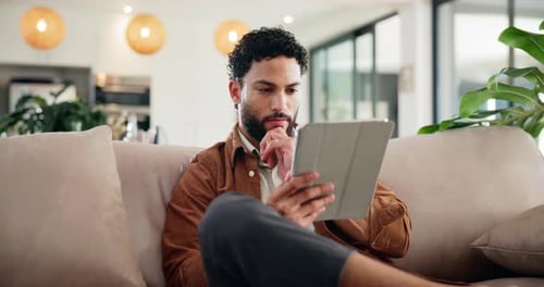 Young Adult Using Tablet on Cream Couch at Home