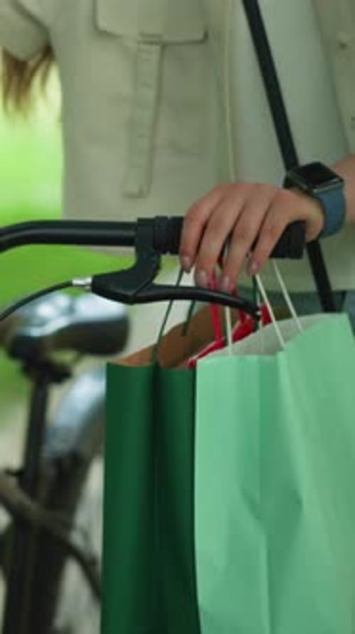 Primer plano de una mujer paseando con bicicleta y bolsas de compras