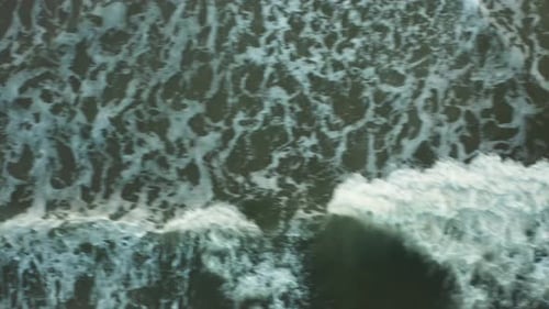 Drone shot over shallow sea water as waves crash, forming beautiful patterns