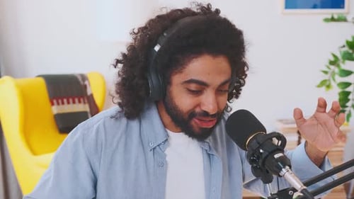 Young Charismatic Arabian Man Blogger in Headphones Tells Story Into Microphone