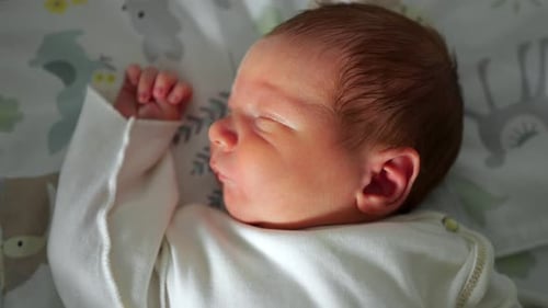 Sleeping newborn baby lying on patterned blanket