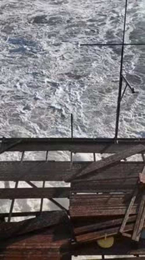 Vertical Video Aerial Escape Morning Storm's Impact Waves in White Foam and a Destroyed Pier