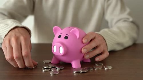 Man keeping money in piggy bank. Close-up.