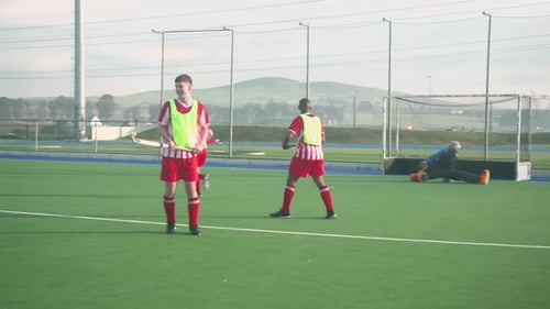 Playing field hockey, men competing intensely on outdoor sports field