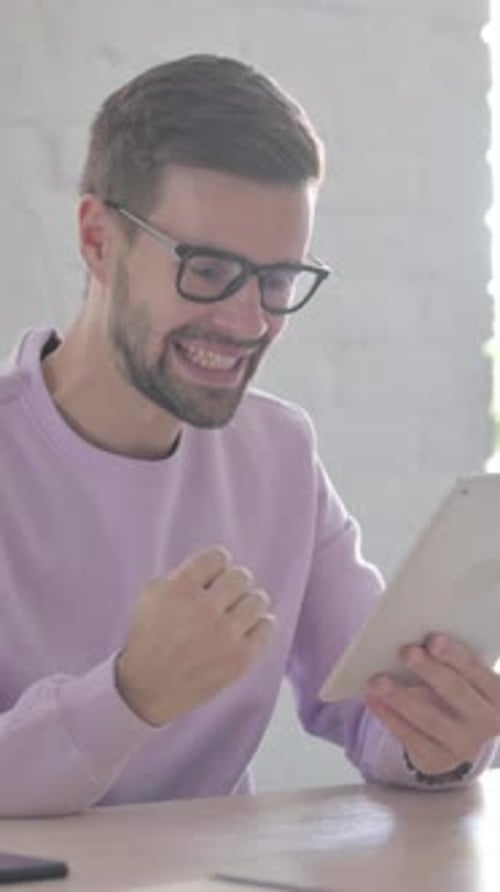Young Man Celebrating on Tablet in Office, Vertical Video