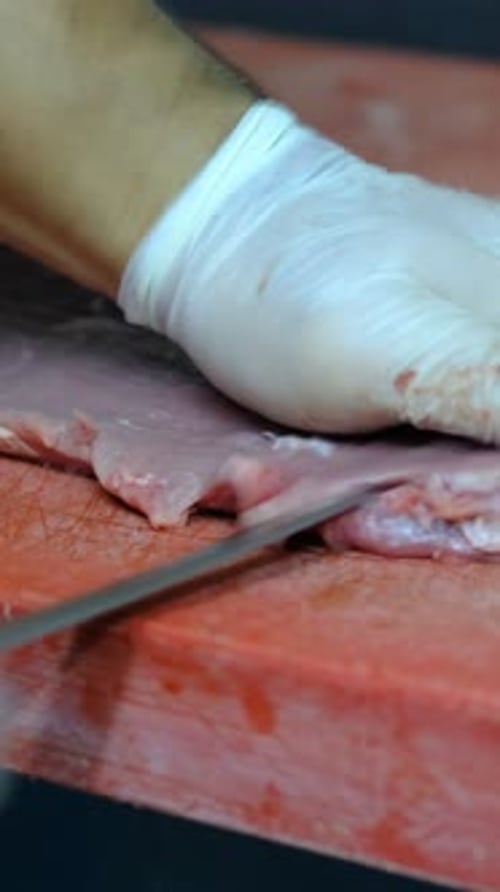Raw Meat Being Sliced on a Cutting Board