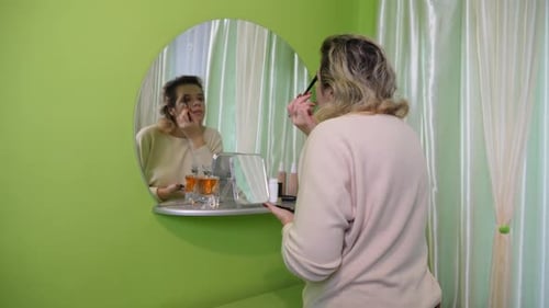 Woman Applying Makeup in Front of Mirror