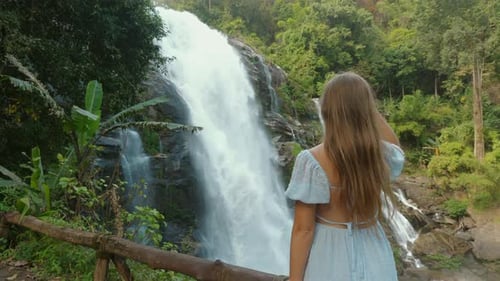 Young Woman Admiring Waterfall in Lush Green Forest Appreciating