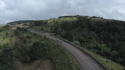4k push out Aerial shot over a group of motorcycle rider crossing a bridge on a hill top country sid