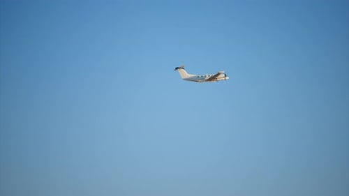 Twin Engine Turboprop Aircraft Flying Through Clear Blue Sky on Sunny Day