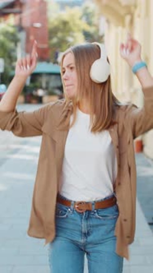 Happy Woman Dancing to Music on City Street