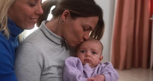 Happy female gay couple having tender moment with their baby son at home - Family, lgbt and love