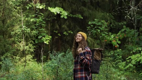 Woman Hiker with Backpack Enjoys Walk Through Dense Green Forest