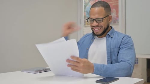 Smiling Young Adult Reading Positive Documents Indoors