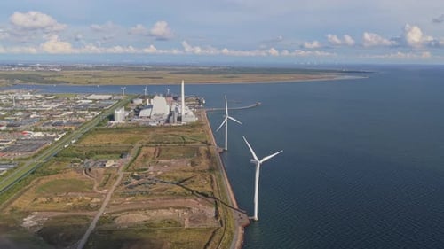 Drone view: wind farm by the Danish coast, turbines aligned at sea.