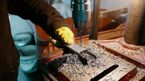 Working man in work glove and Drills Metal with Electric Drill