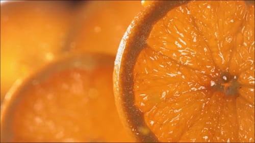 Drop of Orange Juice Flows Down the Surface of a Ripe Juicy Orange Slice